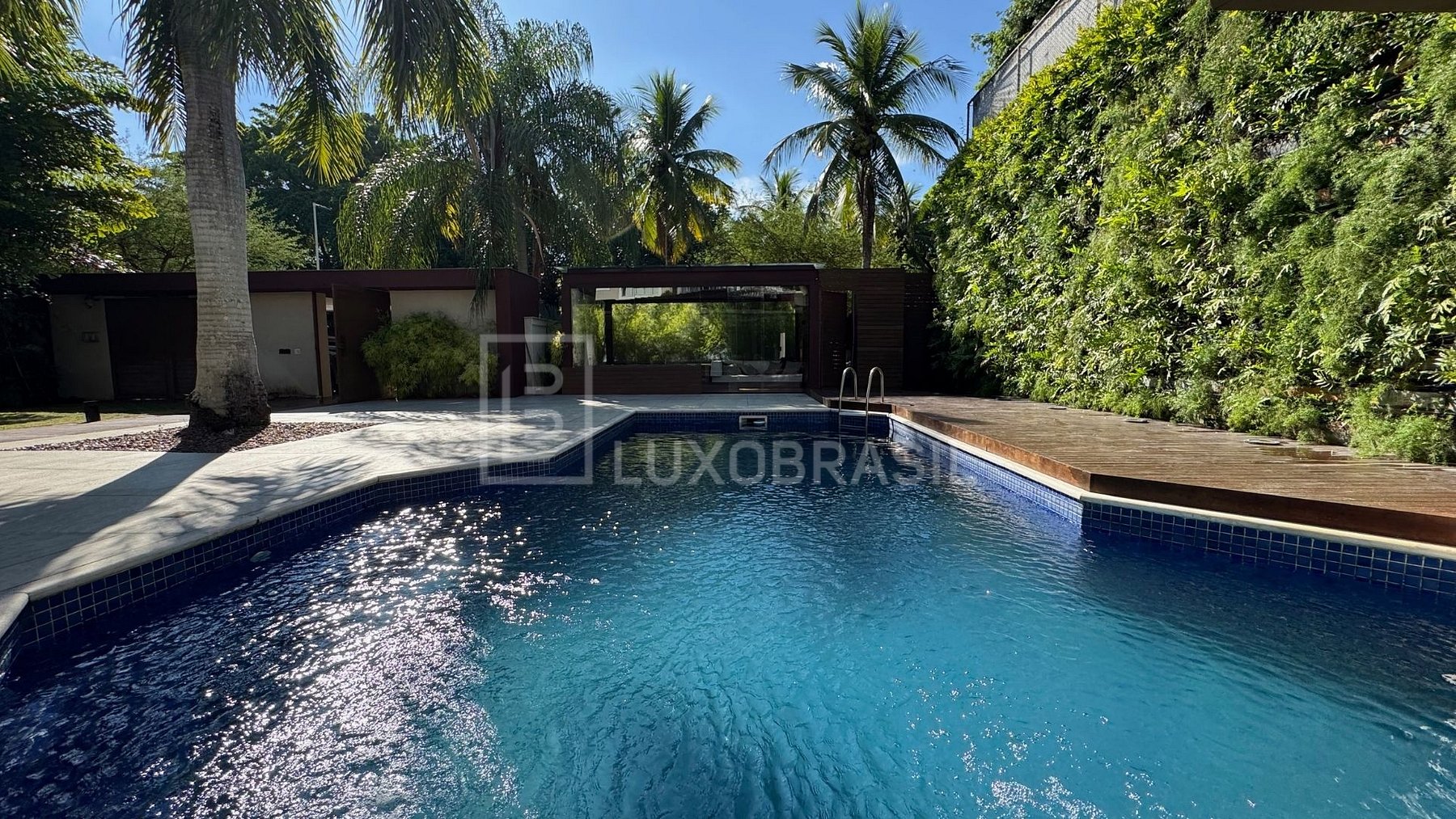 Piscina com parede de jardim vertical e palmeiras