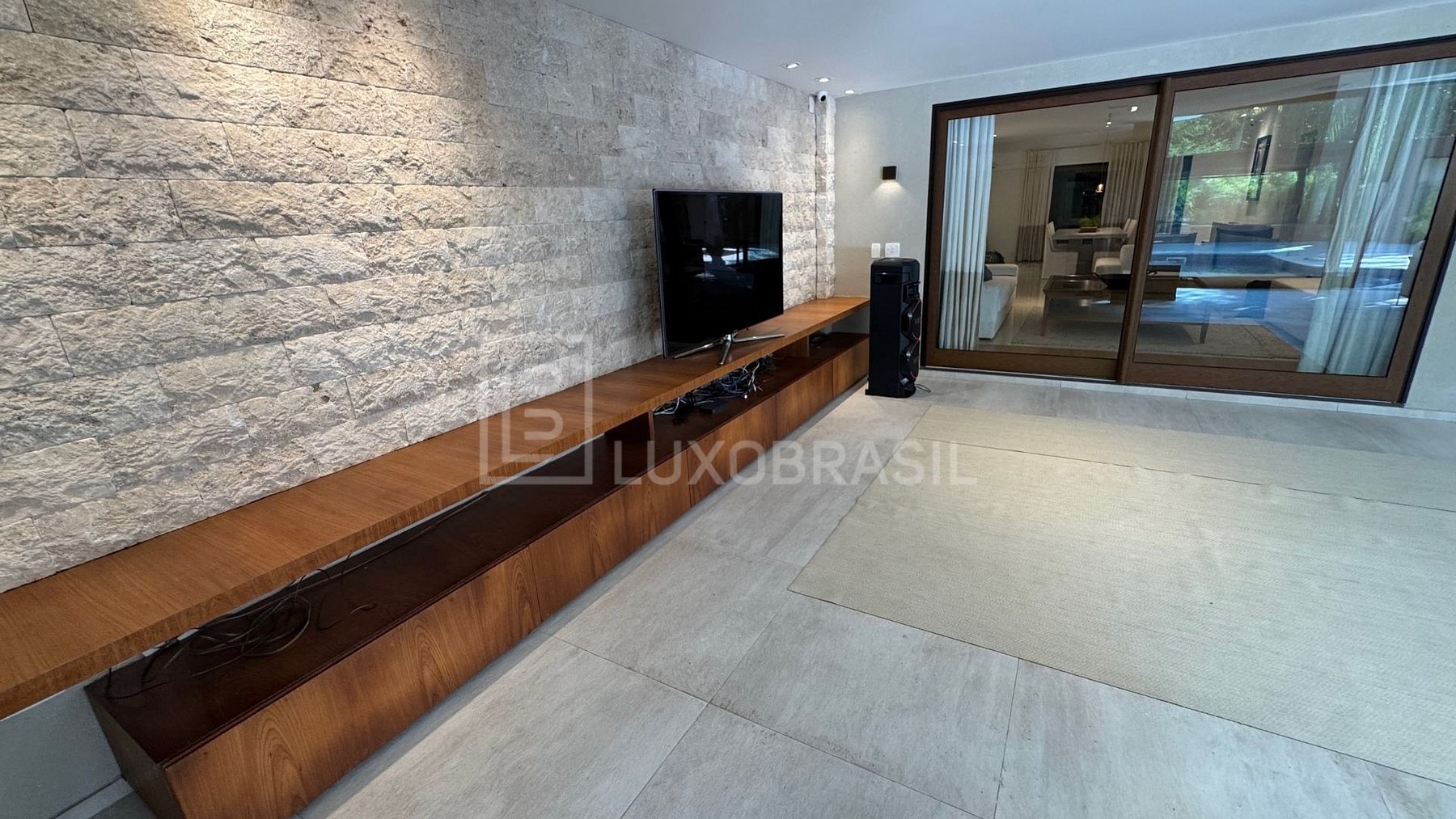 Sala de TV com painel de madeira e parede de travertino