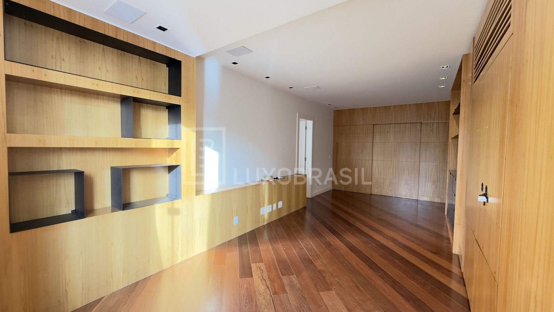 Quarto com estantes de madeira e piso ipê